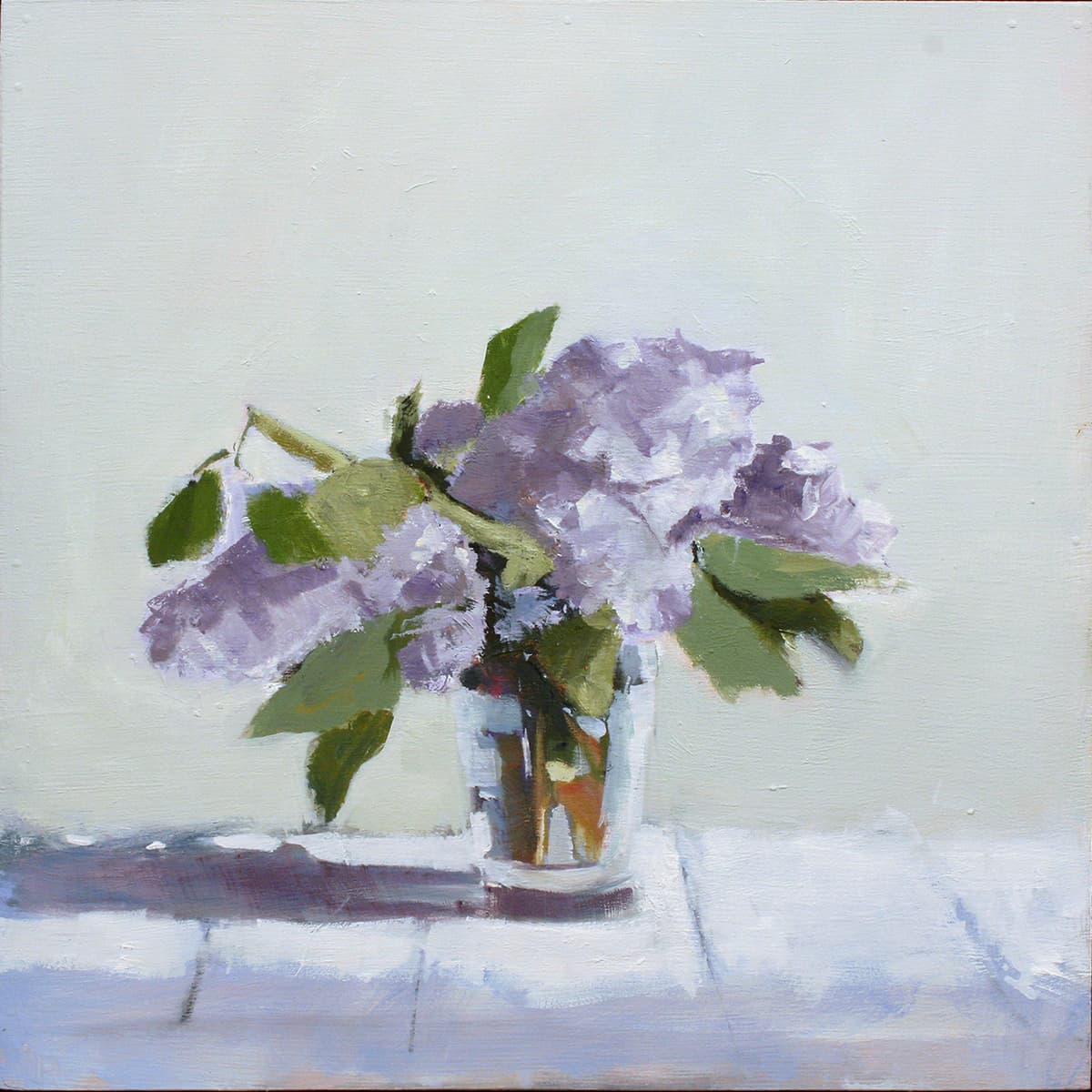 Purple flowers and green leaves in a vase against a soft green background, lilac